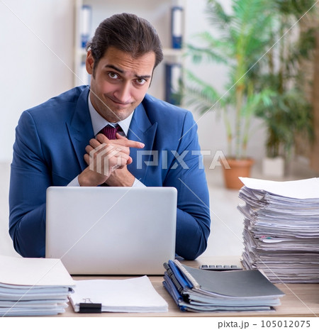 Young male employee unhappy with excessive work in the office 105012075