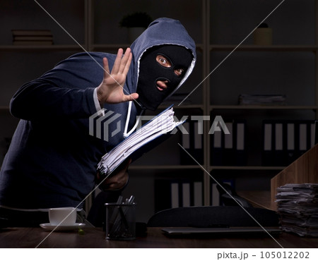 Male thief in balaclava in the office night time Male thief in balaclava in the office night time 105012202