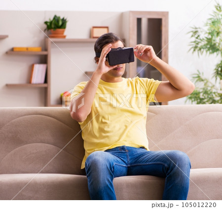 Young man student with virtual glasses at home 105012220