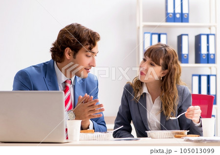 Two colleagues having lunch break at workplace 105013099