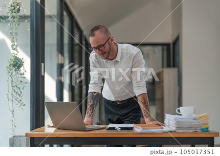 Handsome young businessman working with laptop computer at his desk in office. Happy male entrepreneur Handsome young businessman working with laptop computer at his desk in office. Happy male entrepreneur 105017351