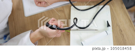 Female doctor using sphygmomanometer checks patient's blood pressure in medical clinic. Female doctor using sphygmomanometer checks patient's blood pressure in medical clinic. 105018458