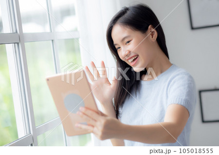 Happiness young asian woman video call with digital tablet in the living room at home. Happiness young asian woman video call with digital tablet in the living room at home. 105018555