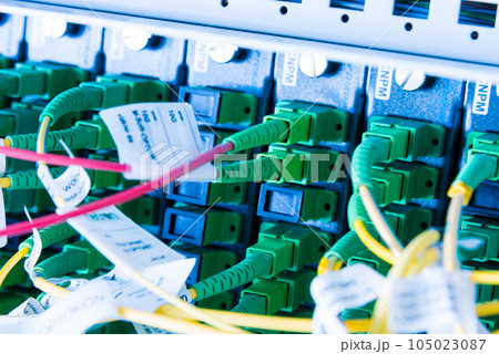 fiber optic cables plugged in network switch panel inside data center 105023087