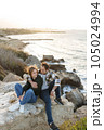 Portrait of a middle-aged couple sitting on a rock at the beach in Cyprus. They are wearing casual clothes 105024994