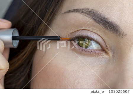 A woman applies eyelash growth product, close up 105029607