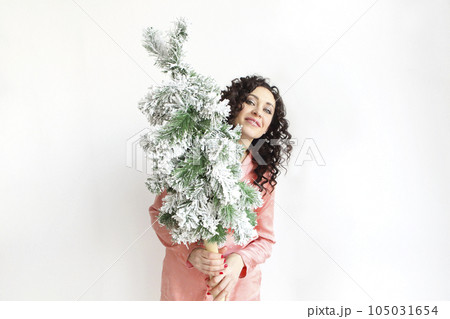 Woman holding small Christmas tree in front of face while standing isolated over white studio background 105031654