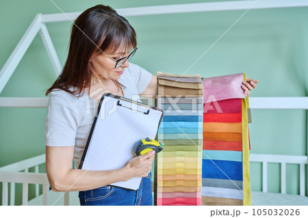 Woman interior designer with fabric tape measure clipboard in client room Woman interior designer with fabric tape measure clipboard in client room 105032026