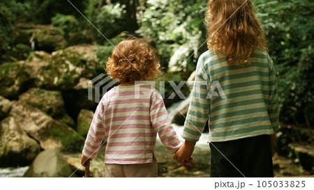 Two little sisters look at beautiful waterfall in the woods 105033825