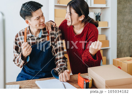 A young Asian couple shows delight and smiles on their faces when they see the sales volume and customer orders exceed expectations. sme or small business family concepts. 105034182