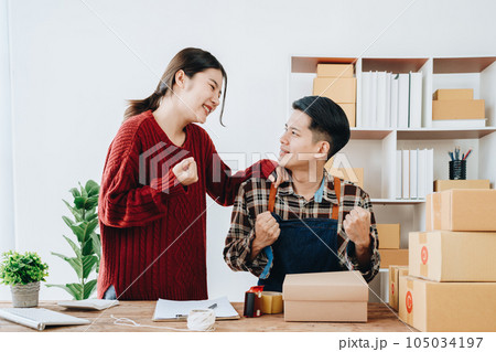 A young Asian couple shows delight and smiles on their faces when they see the sales volume and customer orders exceed expectations. sme or small business family concepts. 105034197