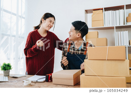 A young Asian couple shows delight and smiles on their faces when they see the sales volume and customer orders exceed expectations. sme or small business family concepts. 105034249