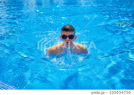 Fit swimmer training in the swimming pool. An overhead view of a man diving into a pool, forming an arrow shape and leaving a trail behind him. Professional male swimmer inside swimming pool. Young 105034750