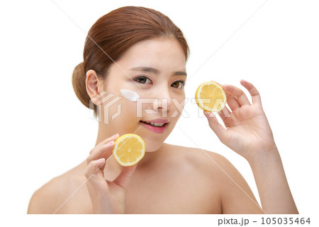 beautiful young woman with clean skin, moisturizing cream and holding a lemon 105035464