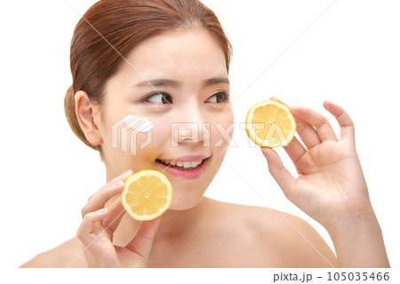 beautiful young woman with clean skin, moisturizing cream and holding a lemon 105035466