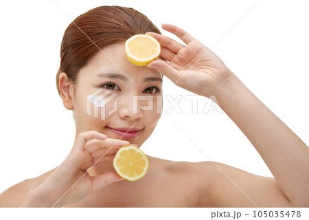 beautiful young woman with clean skin, moisturizing cream and holding a lemon 105035478