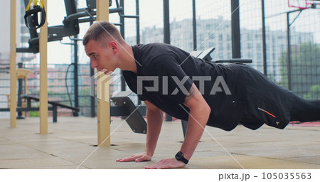 Man doing push up exercises on sports ground. Concept of healthy lifestyle. Outdoors gym. 105035563