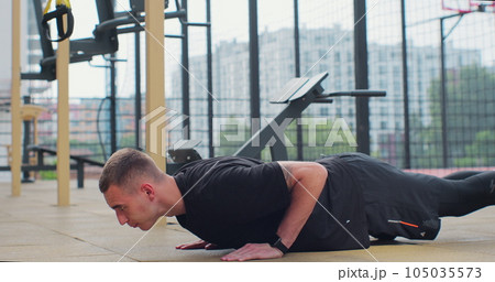 Man doing push up exercises on sports ground. Concept of healthy lifestyle. Outdoors gym. 105035573