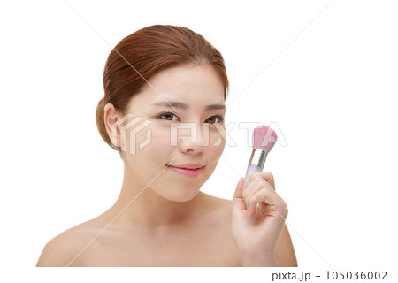 clean-skinned female model holding a makeup brush against a white background clean-skinned female model holding a makeup brush against a white background 105036002