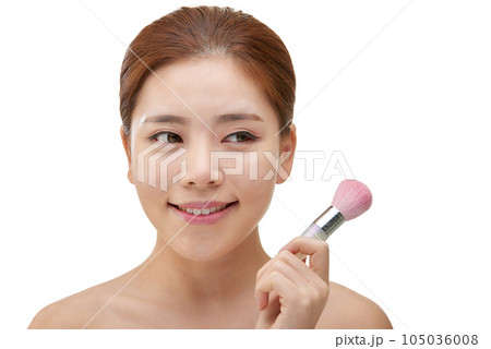 clean-skinned female model holding a makeup brush against a white background clean-skinned female model holding a makeup brush against a white background 105036008