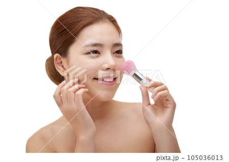 clean-skinned female model holding a makeup brush against a white background 105036013