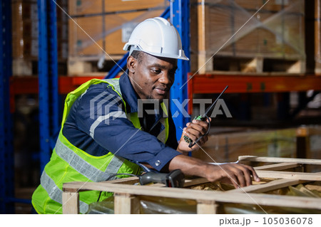 Male american african engineer holding walkie talkie and tablet quality control standing at machine. 105036078