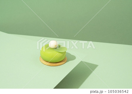A freshly baked pastry with green and white icing, sitting atop a green-hued surface 105036542