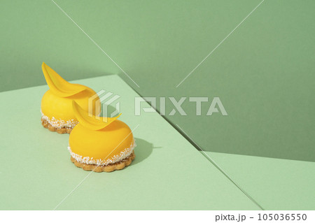 A tray of freshly baked yellow cupcakes with delicious white whipped icing on top and green background 105036550