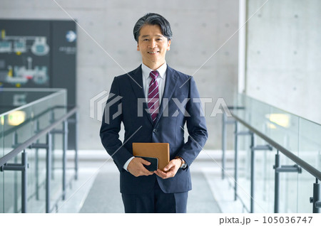オフィスの廊下に立つミドルビジネスマン オフィスの廊下に立つミドルビジネスマン 105036747