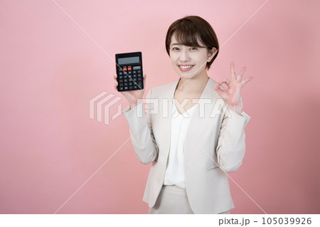 ピンクバックで黒い電卓を持って微笑む女性 ピンクバックで黒い電卓を持って微笑む女性 105039926