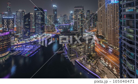Aerial view to Dubai marina skyscrapers around canal with floating boats night timelapse Aerial view to Dubai marina skyscrapers around canal with floating boats night timelapse 105040471