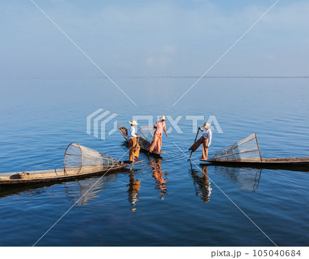 Myanmar travel attraction landmark - three traditional Burmese fishermen with fishing nets on boats at Inle lake in Myanmar famous for their distinctive one legged rowing style Myanmar travel attraction landmark - three traditional Burmese fishermen with fishing nets on boats at Inle lake in Myanmar famous for their distinctive one legged rowing style 105040684