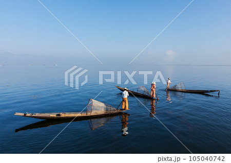 Myanmar travel attraction landmark - traditional Burmese fishermen with fishing nets on boats at Inle lake in Myanmar famous for their distinctive one legged rowing style Myanmar travel attraction landmark - traditional Burmese fishermen with fishing nets on boats at Inle lake in Myanmar famous for their distinctive one legged rowing style 105040742