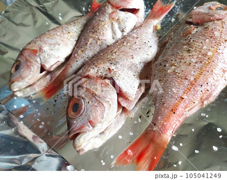 Cooking fresh fish on foil. Top view and close up. Healthy sea food. Diet meal preparation. 105041249