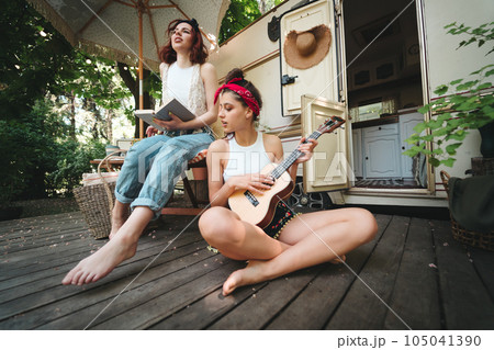 Happy hippie friends are having a good time together with guitar in camper trailer. Holiday, vacation, trip concept. 105041390
