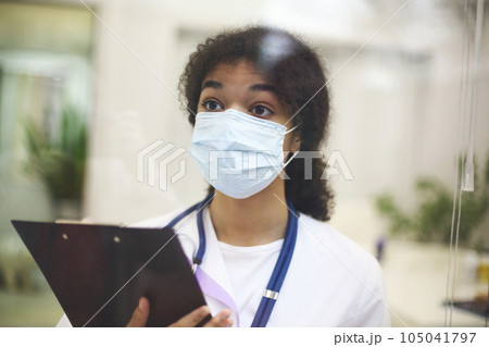 Young tired  african american medical worker wearing protective face mask with x-ray scan in hands 105041797