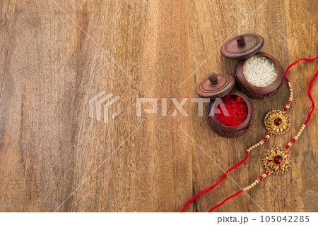 Raksha Bandhan background with Rakhi string, Rice Grains and Kumkum Raksha Bandhan background with Rakhi string, Rice Grains and Kumkum 105042285