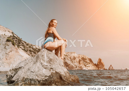 Woman travel summer sea. A happy tourist in a blue bikini enjoying the scenic view of the sea and volcanic mountains while taking pictures to capture the memories of her travel adventure. Woman travel summer sea. A happy tourist in a blue bikini enjoying the scenic view of the sea and volcanic mountains while taking pictures to capture the memories of her travel adventure. 105042657