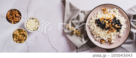 Homemade cottage cheese with fresh blackcurrants and walnuts on a plate top view web banner 105043043