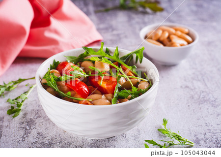 Appetizing salad of canned white beans, cherry tomatoes and arugula in a bowl 105043044