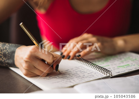 Close-up woman's hand holding a pencil and writing information in a notebook 105043586