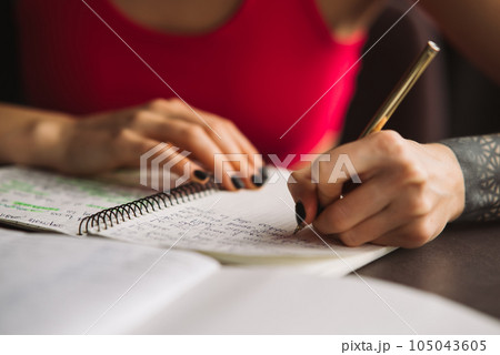 Close-up woman's hand holding a pencil and writing information in a notebook Close-up woman's hand holding a pencil and writing information in a notebook 105043605