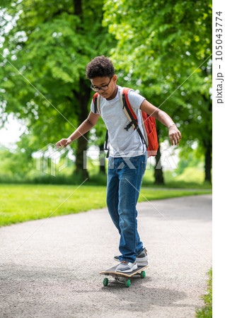 A curly-haired boy on a longboard in the park A curly-haired boy on a longboard in the park 105043774
