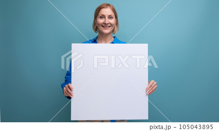 blonde middle aged woman holding note board with mockup on blue background copy space 105043895