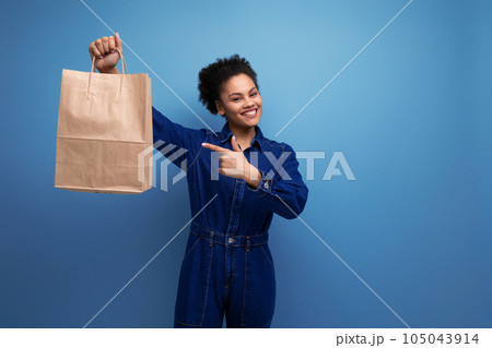 happy positive activist young hispanic brunette woman with fluffy curly hair in blue denim suit 105043914