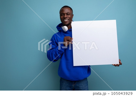handsome young african man showing a white board with a mockup for advertising on the background 105043929