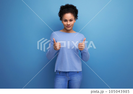 confident pretty brunette lady with afro curls showing super hand gesture on blue background with confident pretty brunette lady with afro curls showing super hand gesture on blue background with 105043985