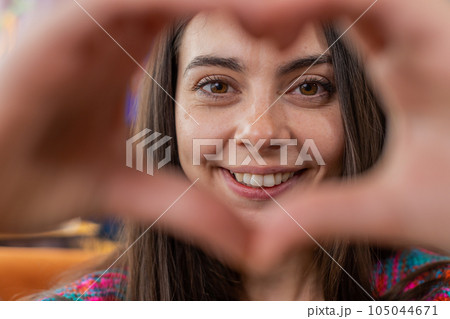 Happy young woman girl makes symbol of love showing heart sign to camera express romantic feelings Happy young woman girl makes symbol of love showing heart sign to camera express romantic feelings 105044671
