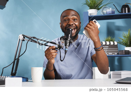 Excited african american blogger sharing positive insight with internet channel subscribers. Happy cheerful vlogger giving good news to audience while filming video for blog 105045568