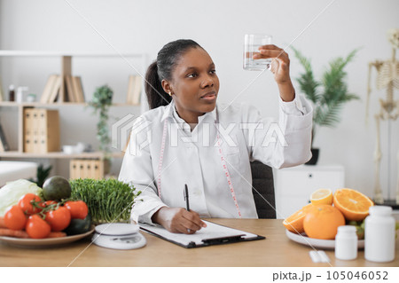 Nutrition specialist checking fluid in glass at workplace 105046052